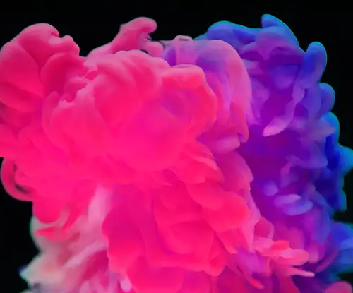 abstract image showing a pink, purple and blue cloud expanding over a black background