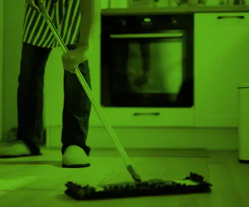 Image shows the lower half of a man as he mops the floor in a home kitchen