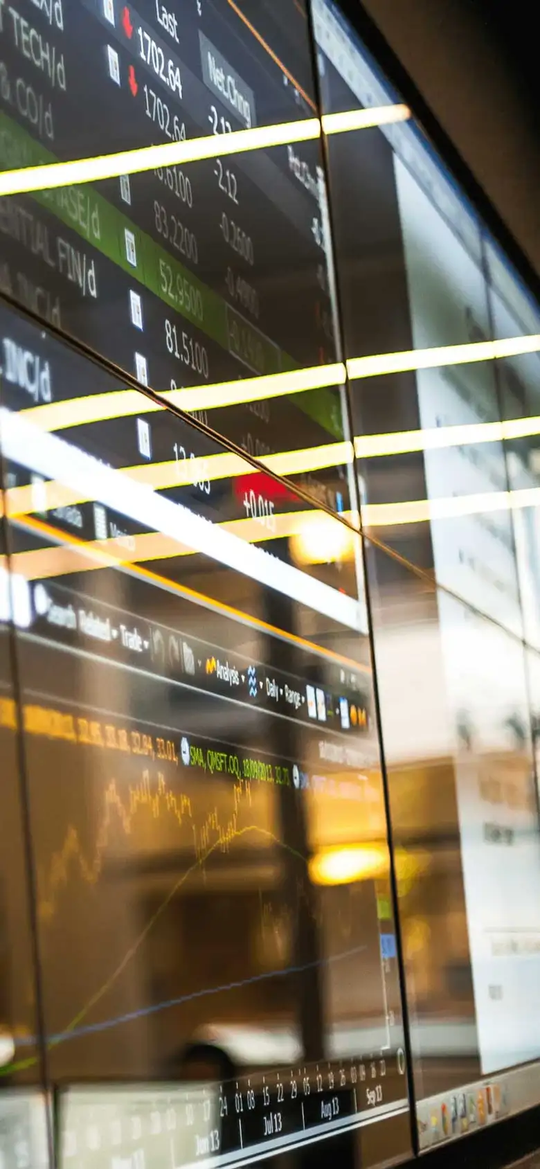 A wall of screens displays stock data.