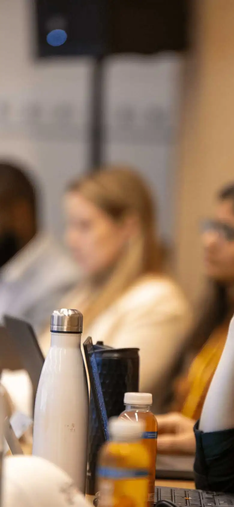 A row of students look at an off screen speaker.