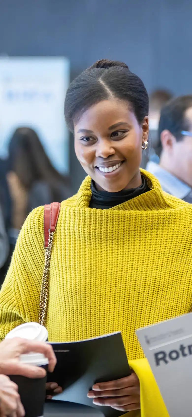 A woman in a yellow sweater speaks to two other women