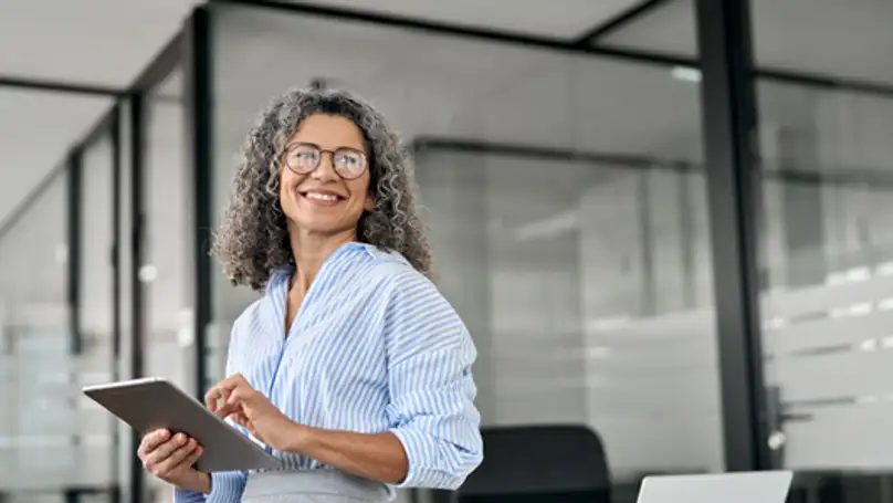 A woman with greying hair smiling off in an office