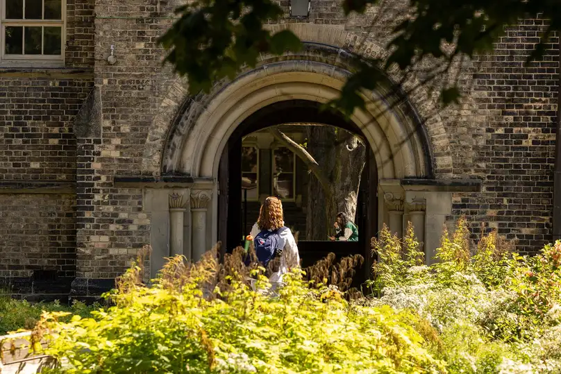 Student entering a stone archway at U of T
